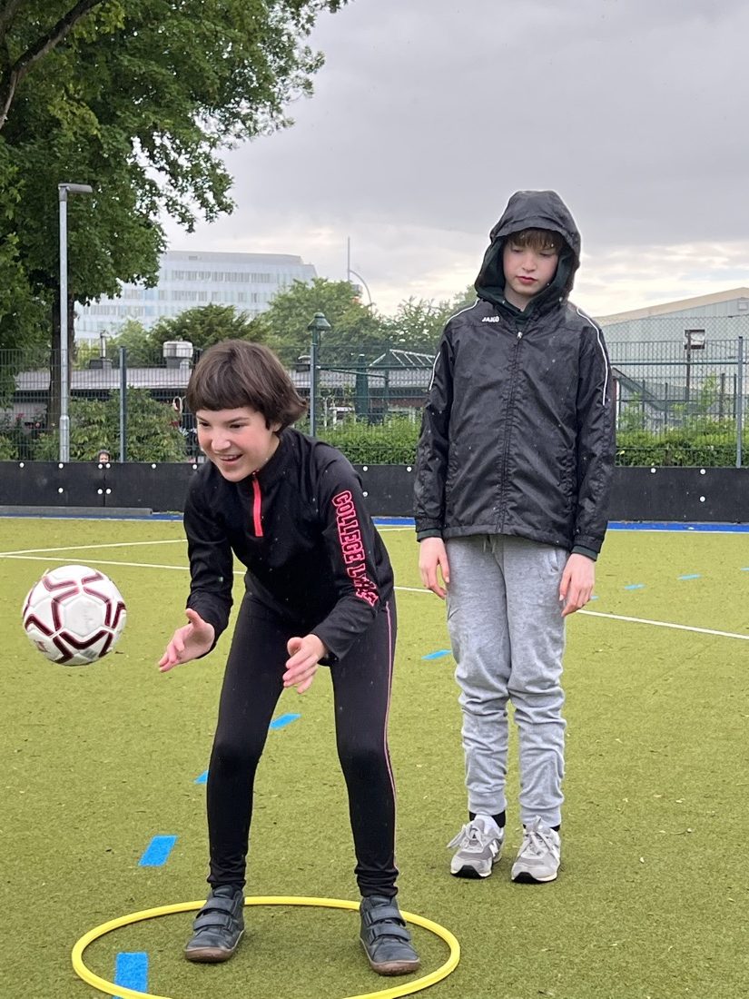 Zwei Kinder konzentrieren sich auf eine Übung mit Ball und Reifen