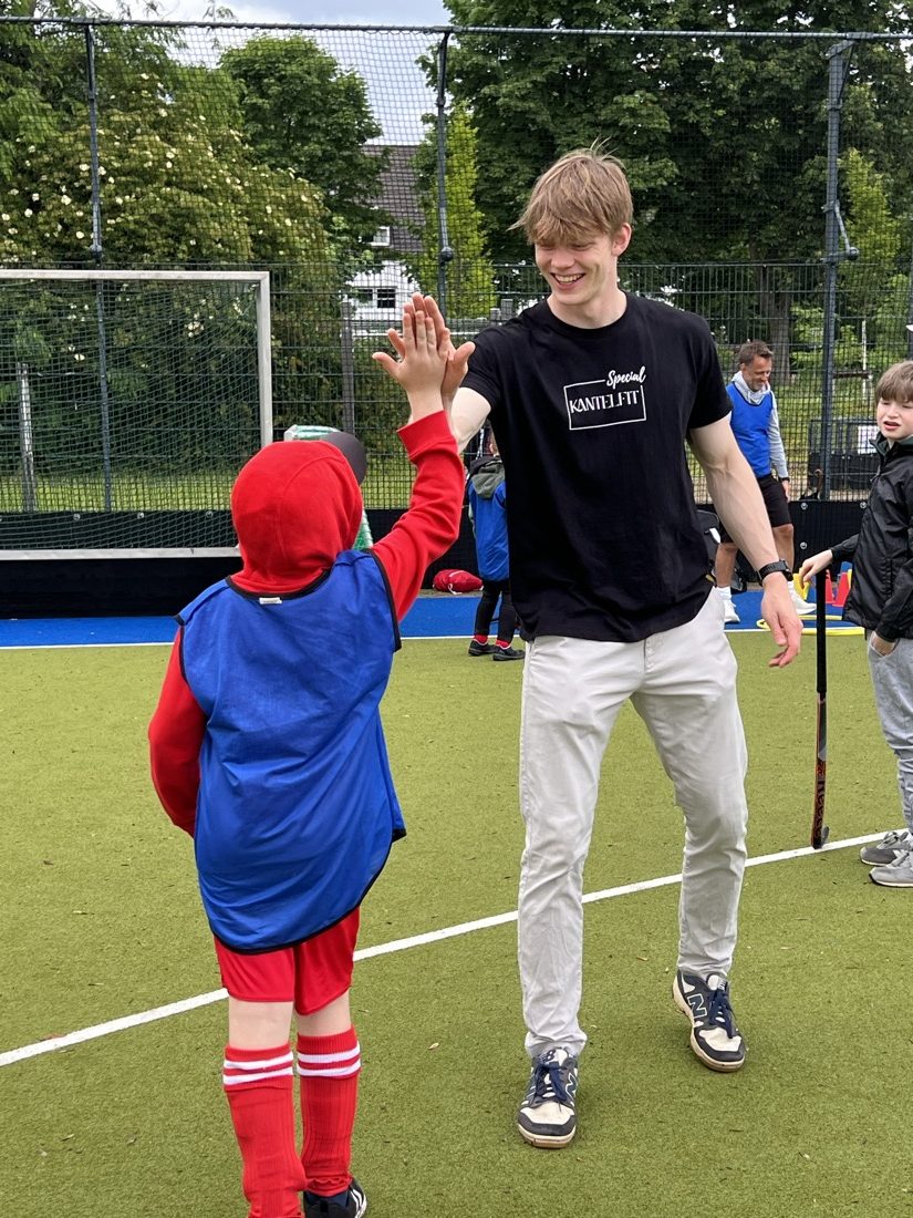 Trainer gibt einem kleinen Spieler im Superhelden-Kostüm ein High Five