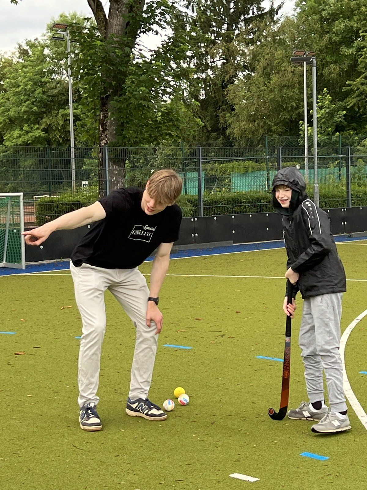 Trainer erklärt einem Teilnehmer mit Schläger und Ball die nächste Übung