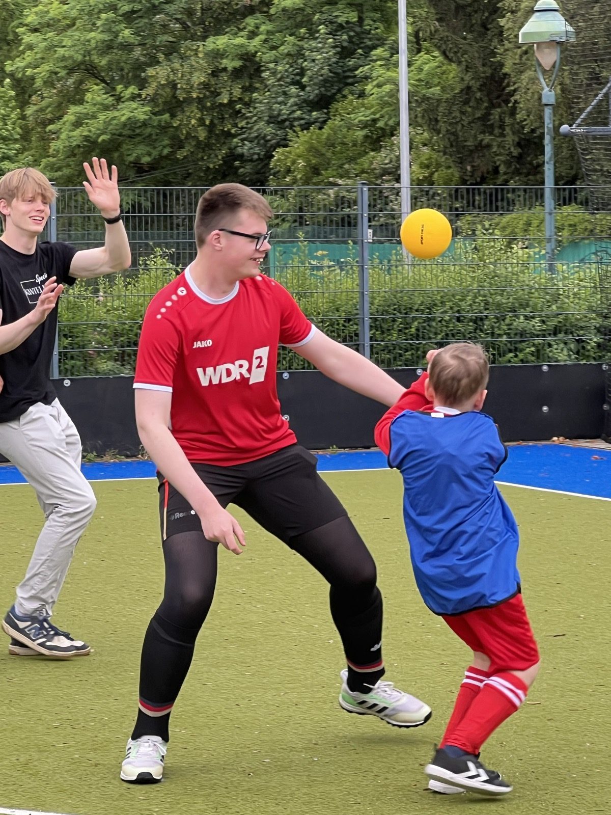 Trainer und Kind spielen sich lachend einen Ball zu