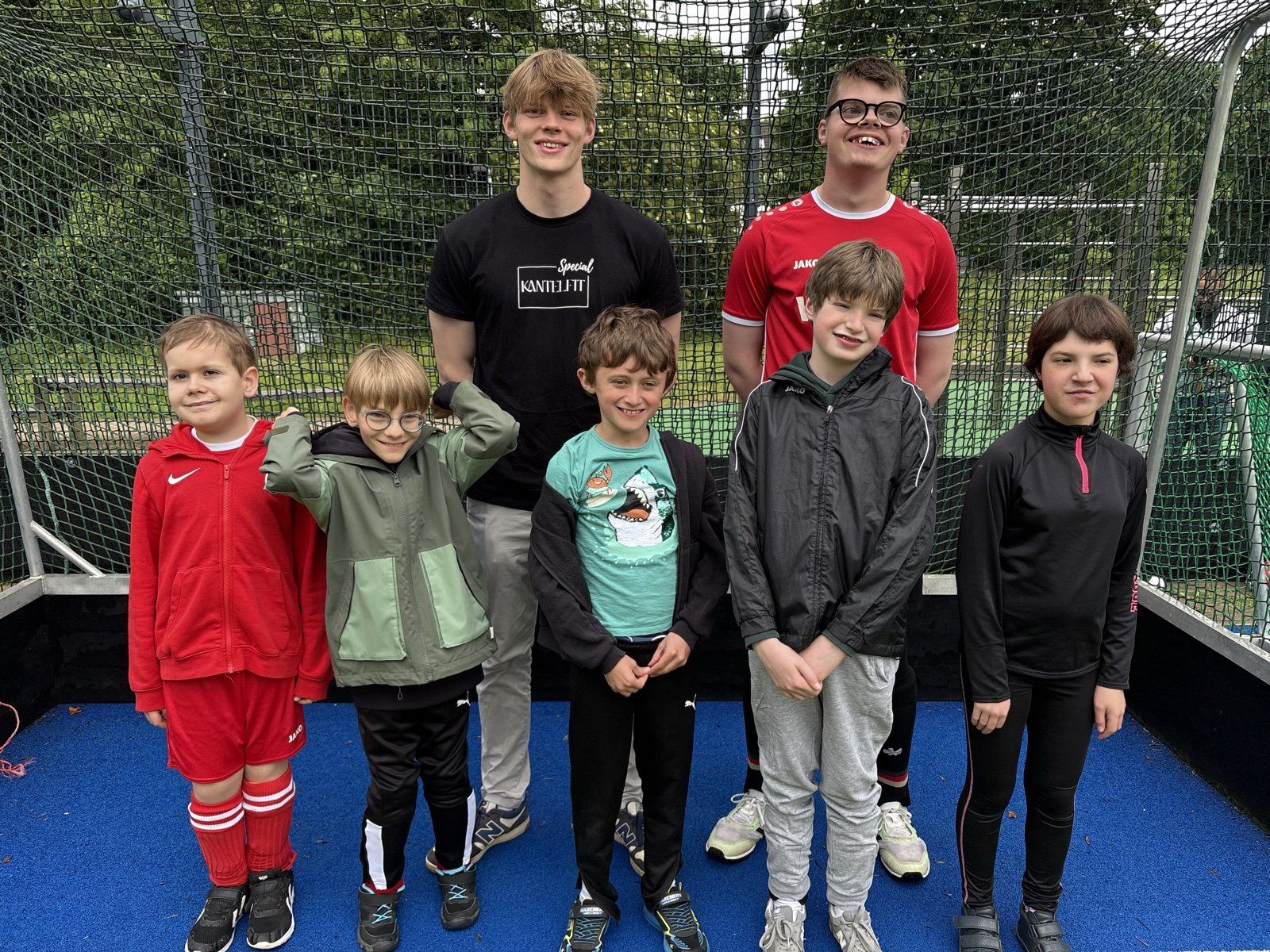 Trainer und Kinder stehen als Team zusammen vor dem Hockeytor