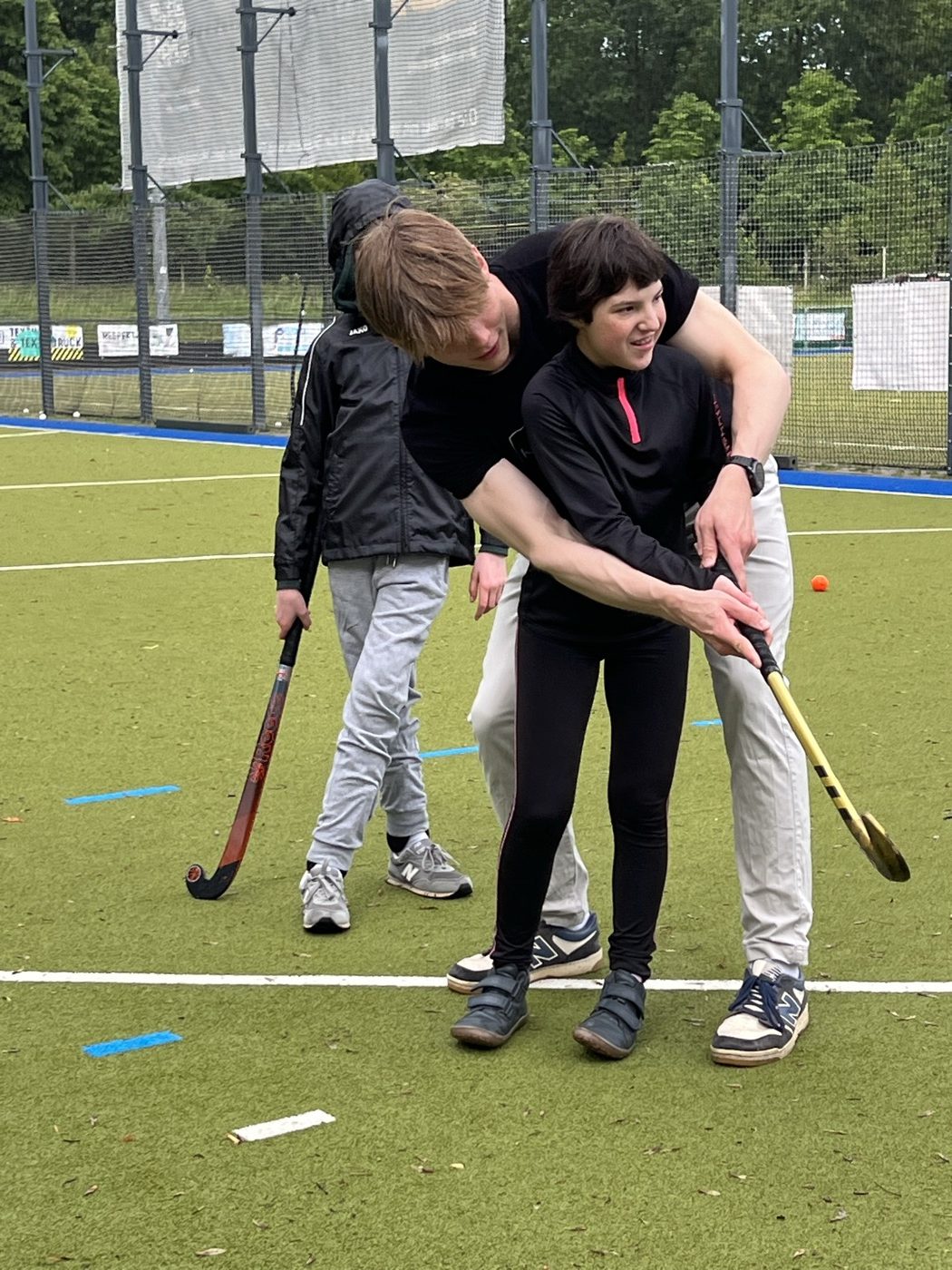 Trainer und Spielerin schwingen gemeinsam den Hockeyschläger